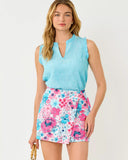 Woman wearing a light blue sleeveless top and a colorful floral skirt on a white background